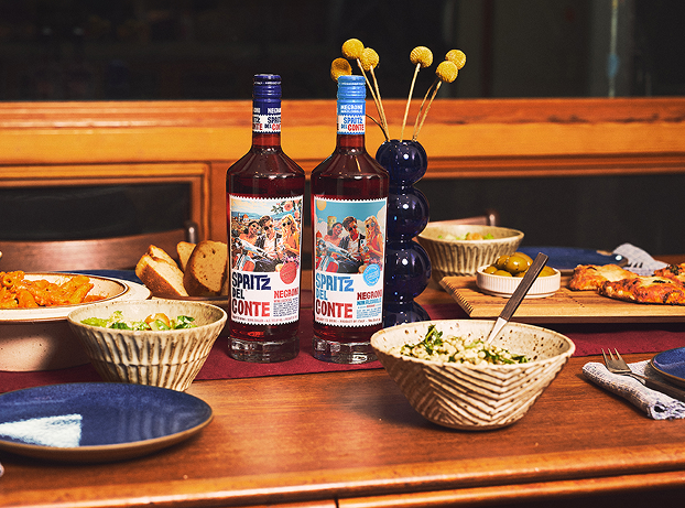 A bottle of Spritz Del Conte Negroni Non-Alcoholic alongside a dinner party spread